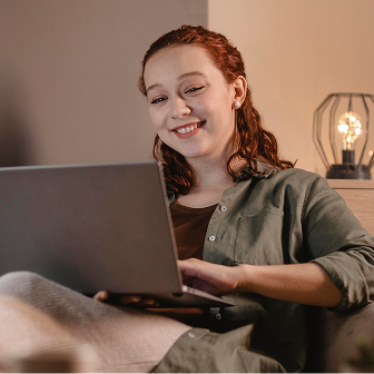 smiley woman using laptop home couch